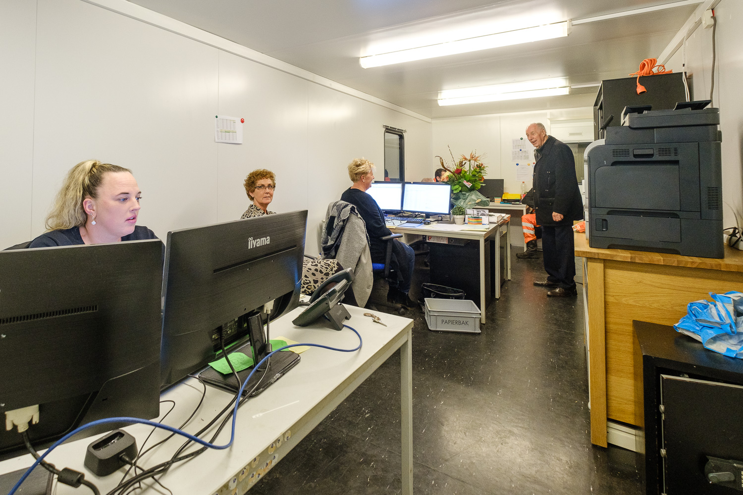 Ilona Ros (L) en Trudy Spronk (derde van links) in het mobiele kantoor in Spijk